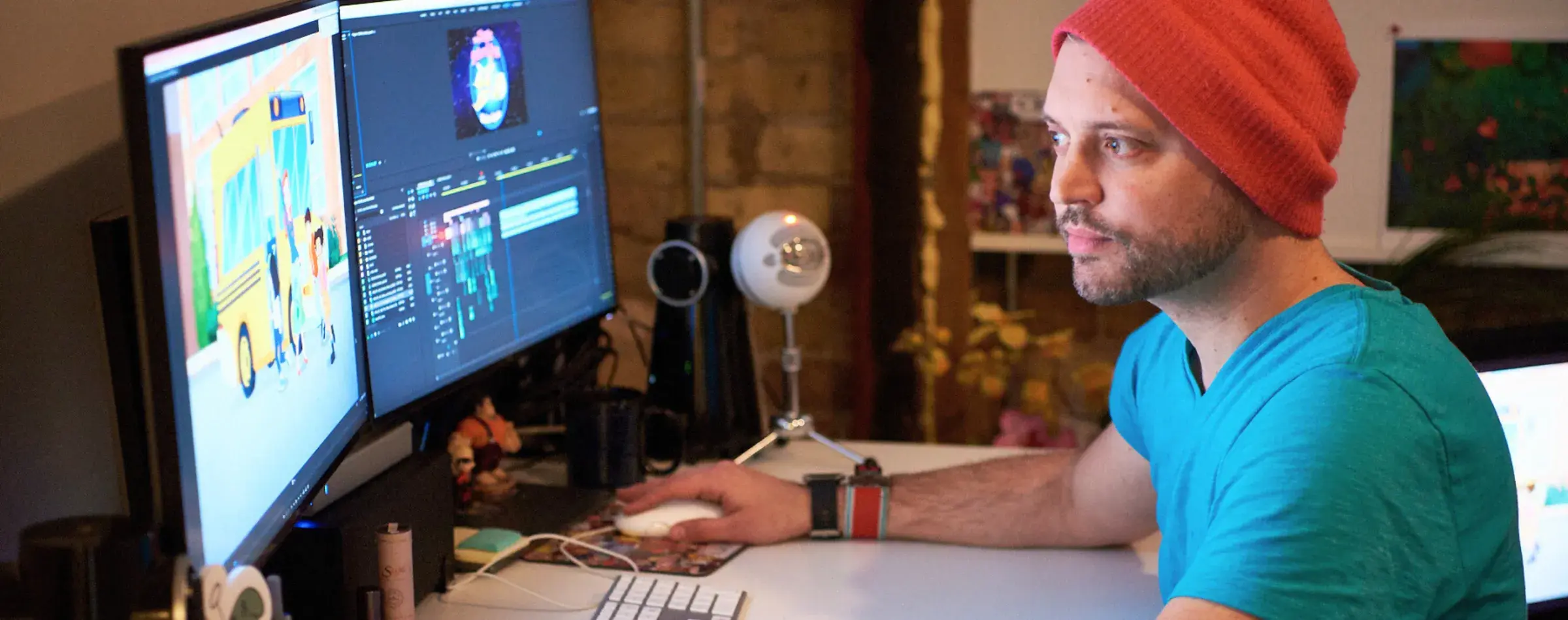 A person working alone at a desk with two monitors, one displaying animation software.
