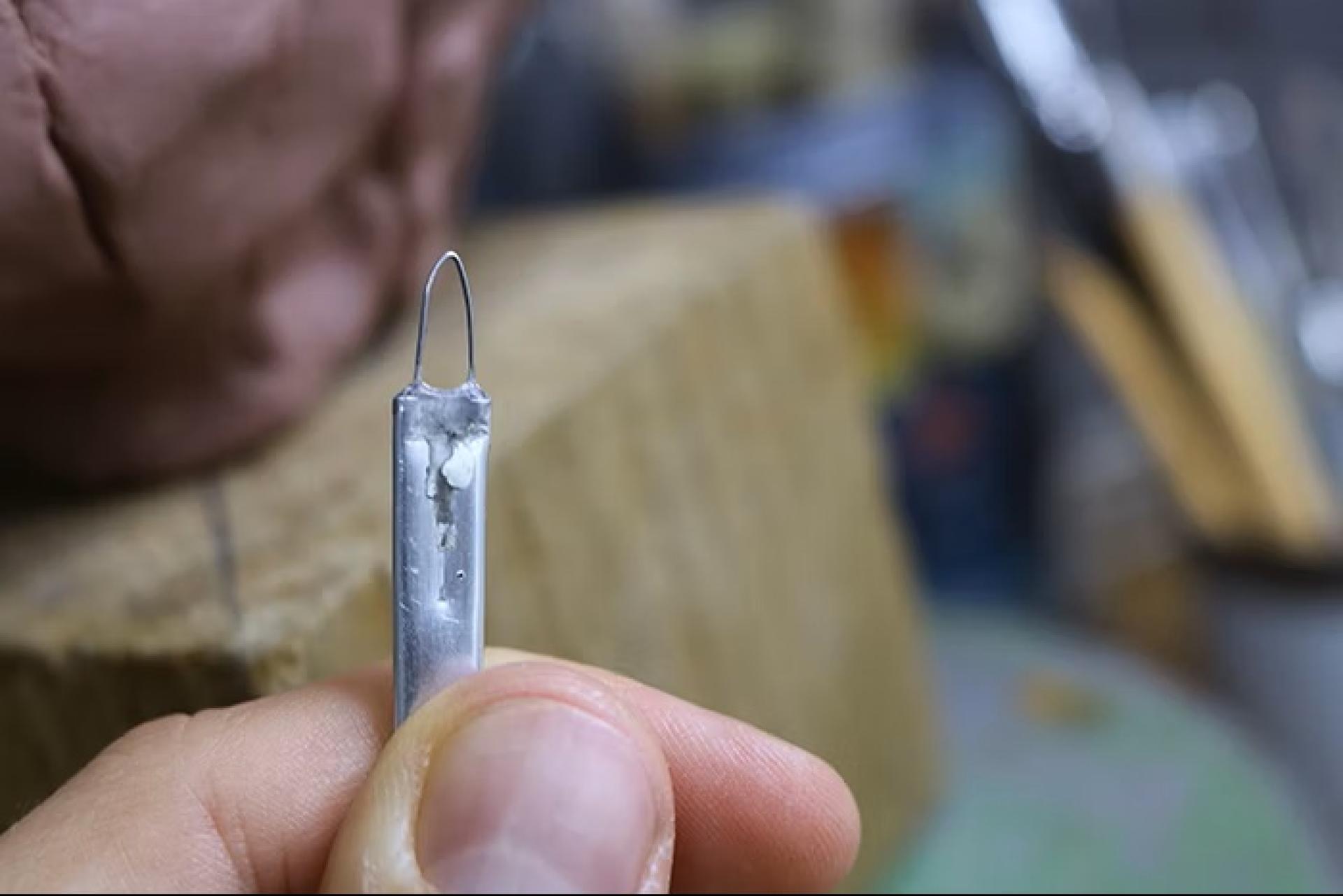 Wire loop sculpting tool held close-up for clay detailing.