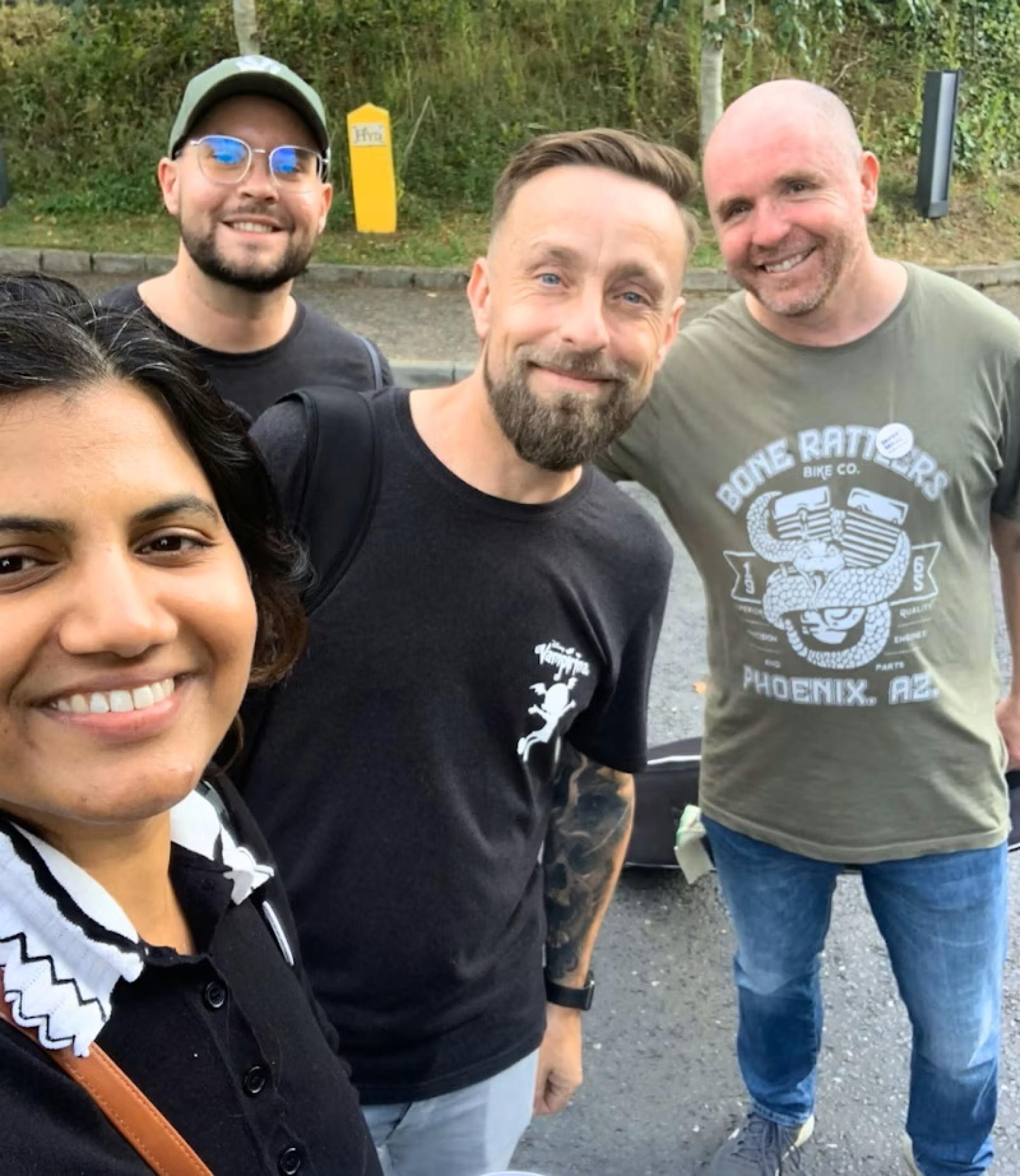 Group photo of four adults outdoors, casually dressed.
