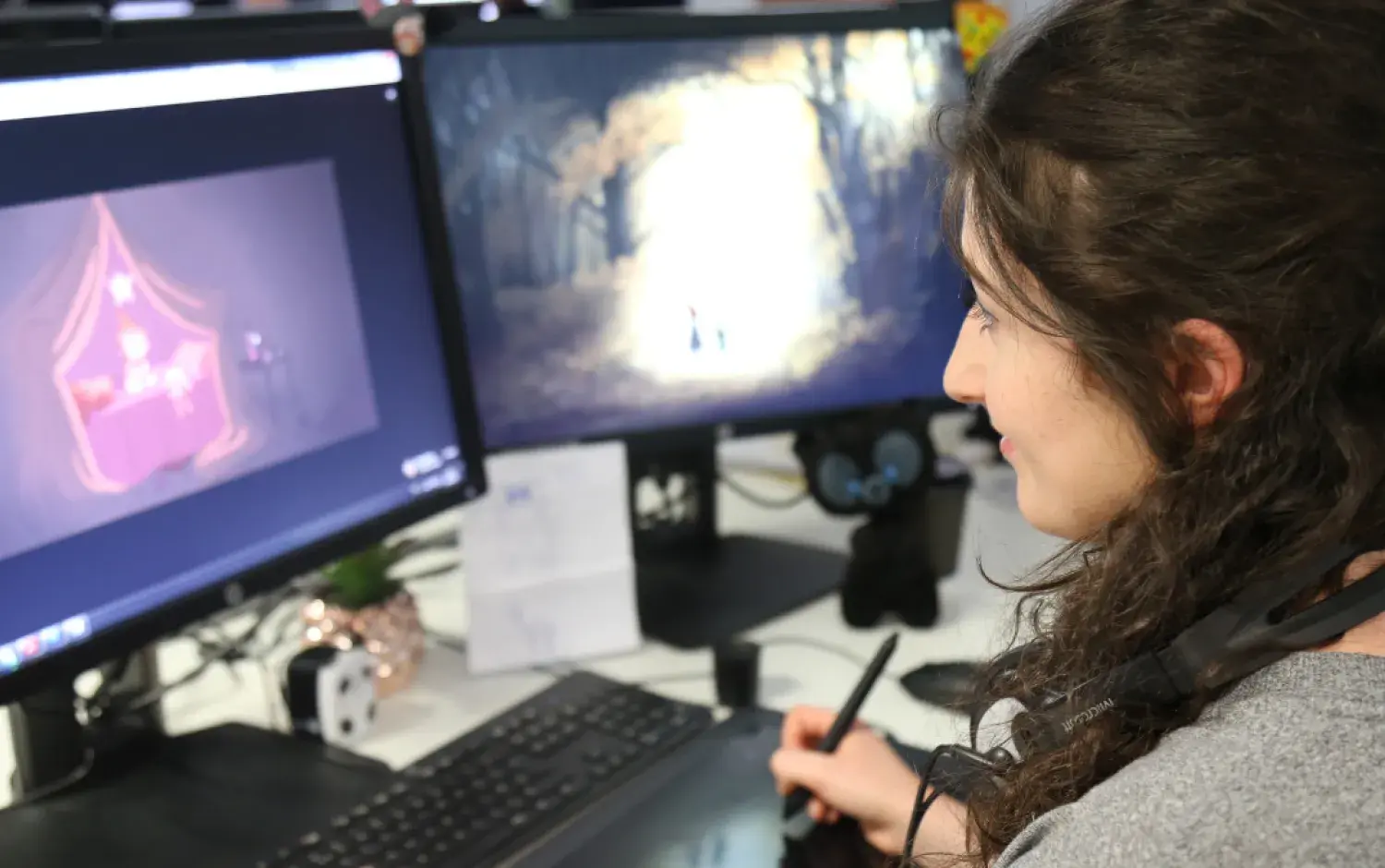 Computer workstation with dual monitors displaying digital artwork.