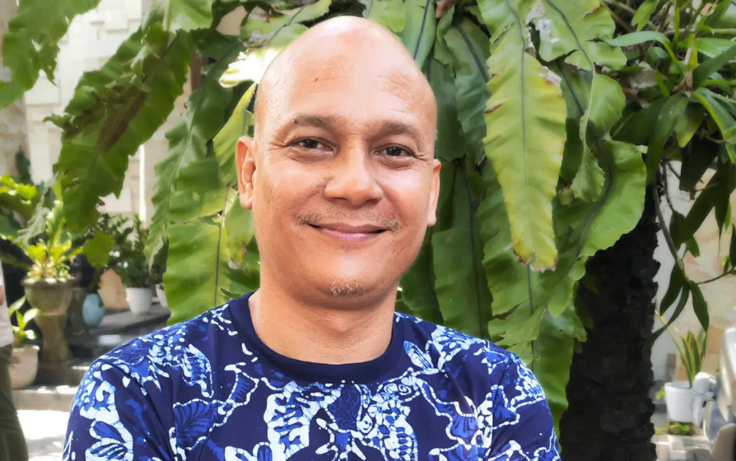 A photo of Faseh Hulisan standing outside, a tree in the background.