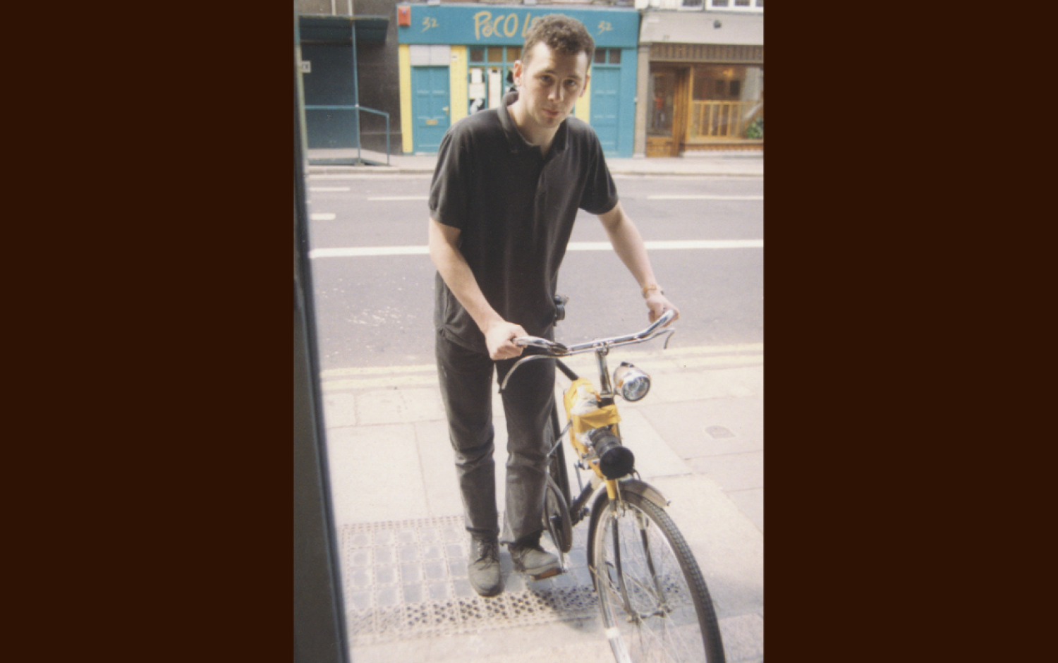 A photo of Cathal Gaffney in 1994 in Dublin standing outside a doorway with a bike.