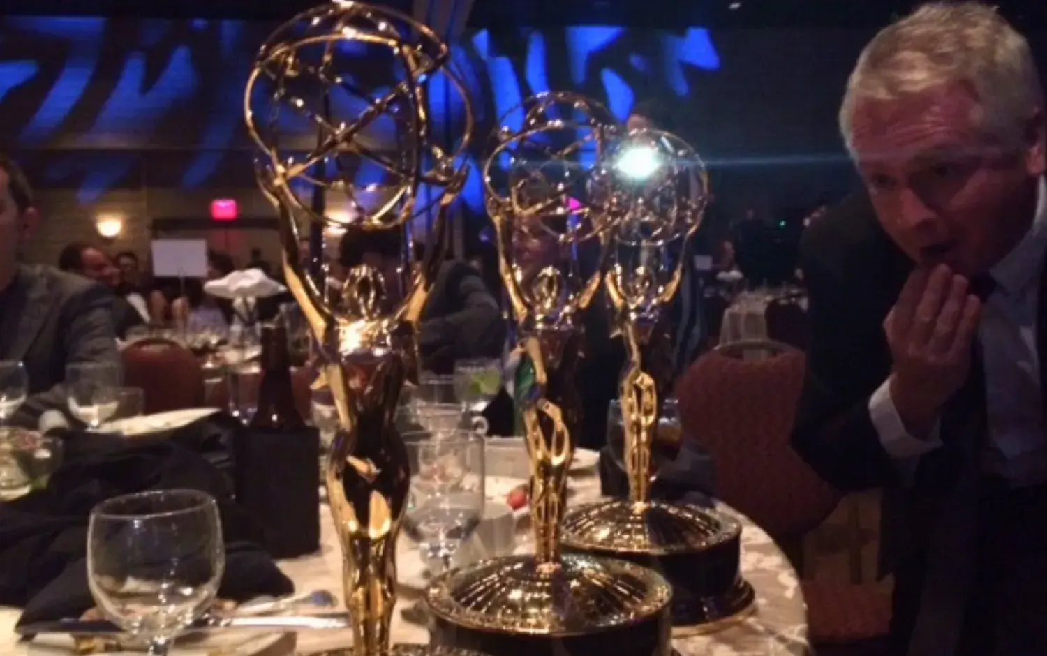 Three Emmy statuettes on a dinner table at the ceremony.