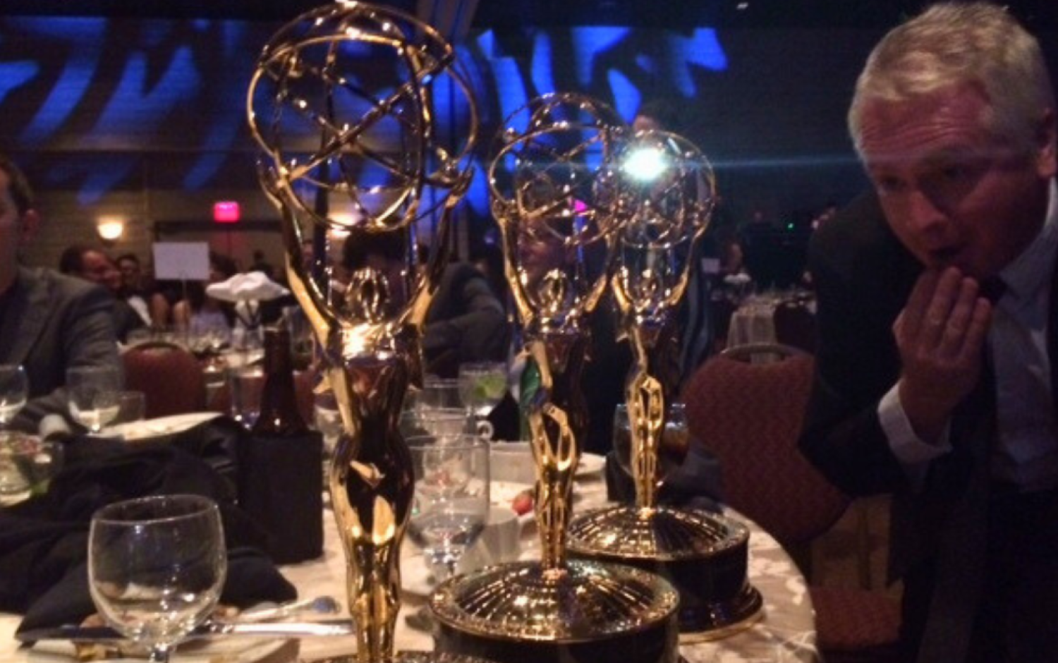 Three Emmy statuettes on a dinner table at the ceremony.