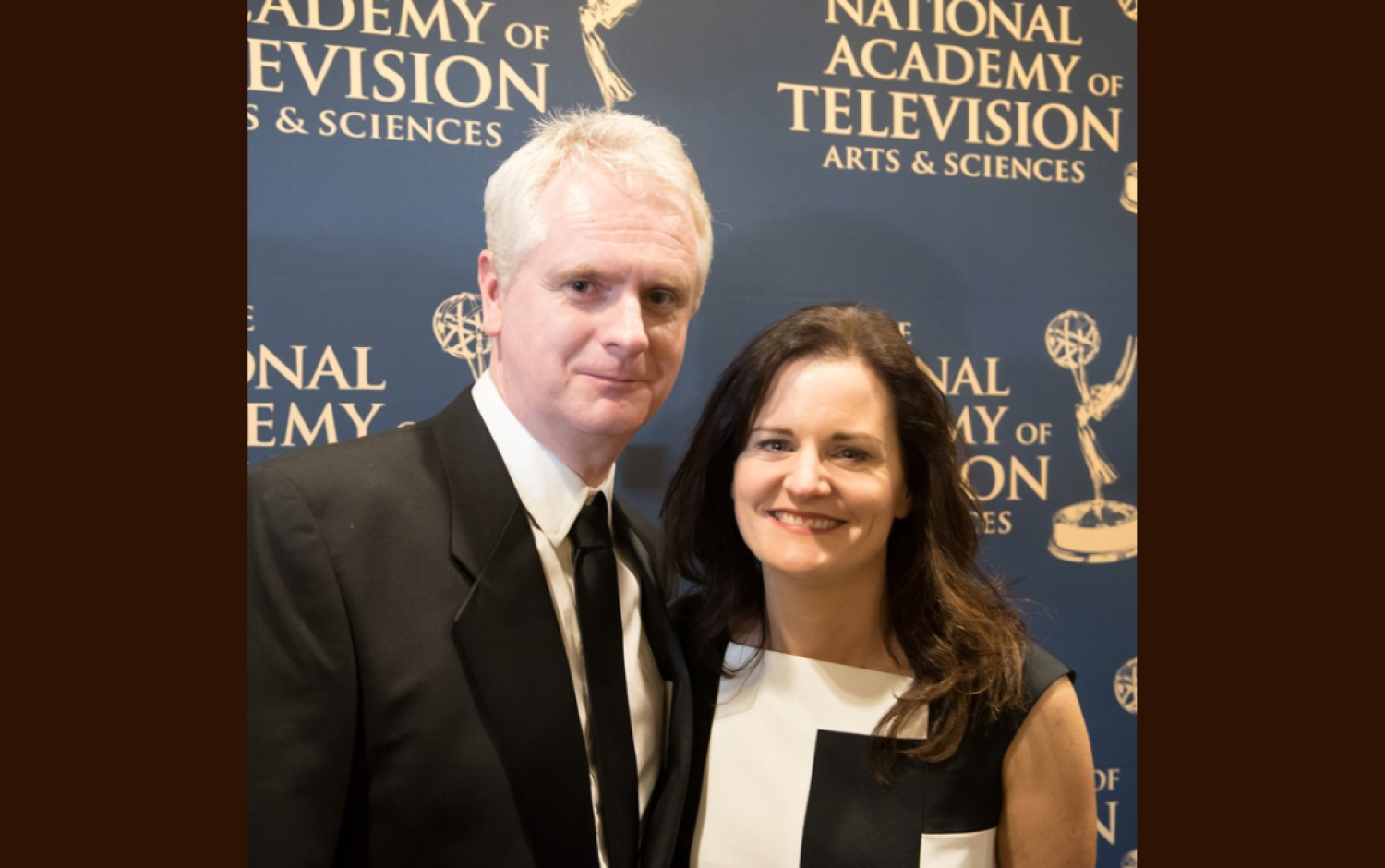 Two people posing in front of a National Academy of Television Arts & Sciences backdrop.