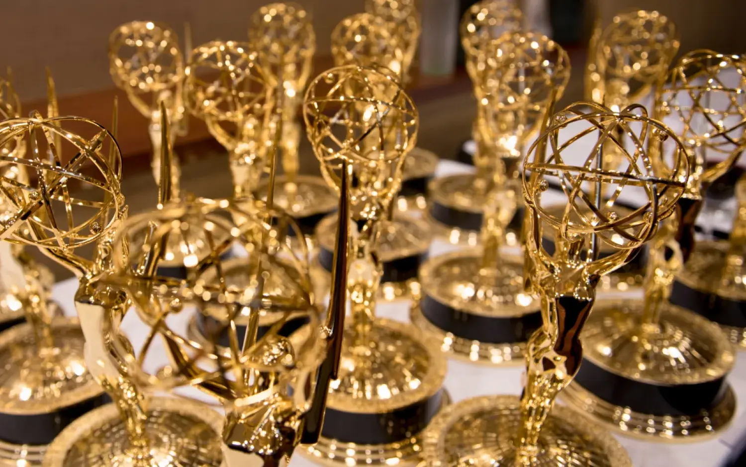 Close-up of multiple Emmy Award trophies arranged on a table.