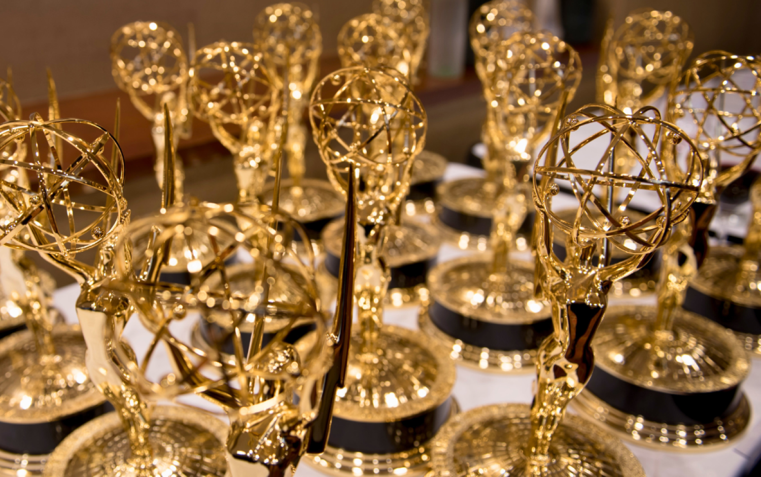 Close-up of multiple Emmy Award trophies arranged on a table.