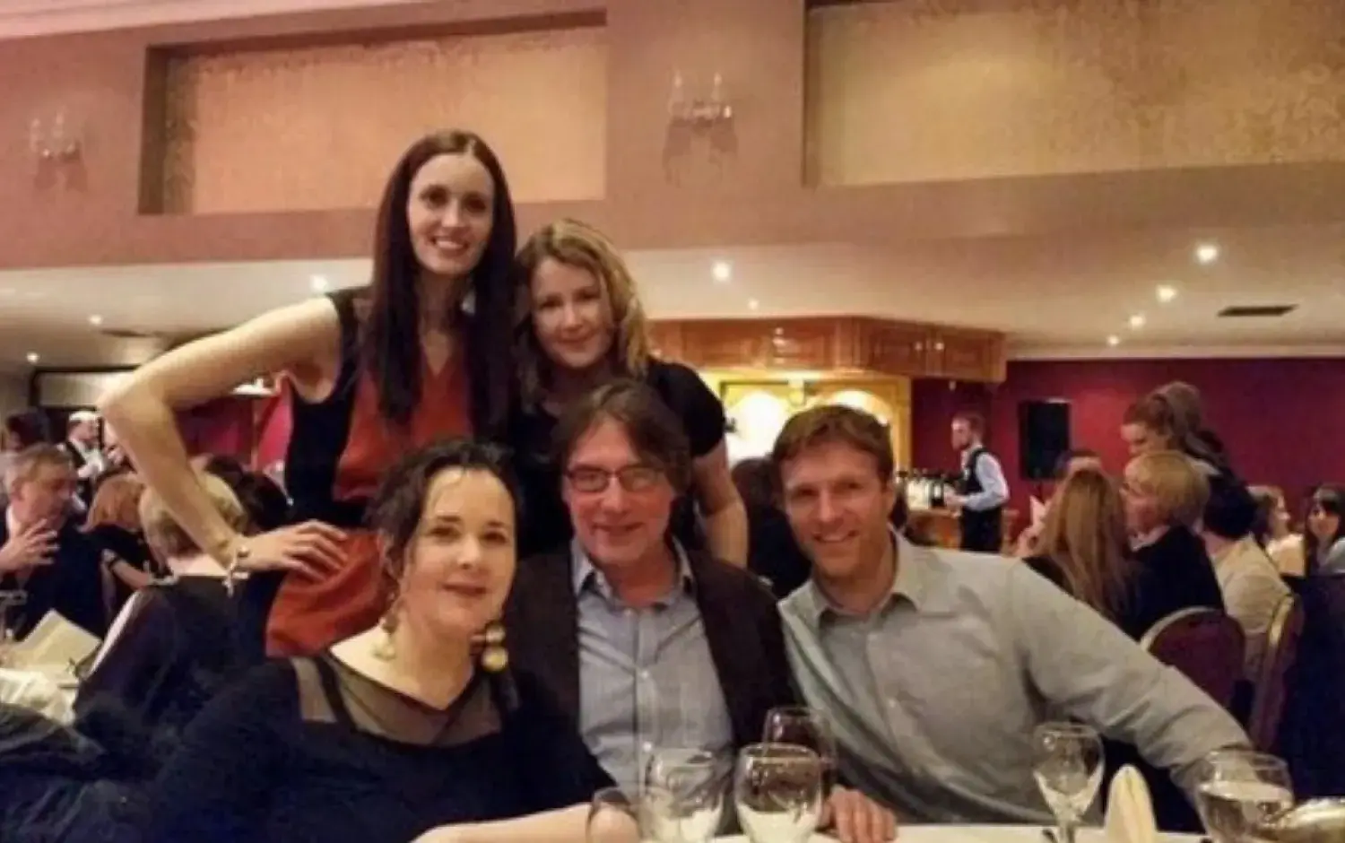 Group photo at a banquet table during an event with wine glasses and table settings.
