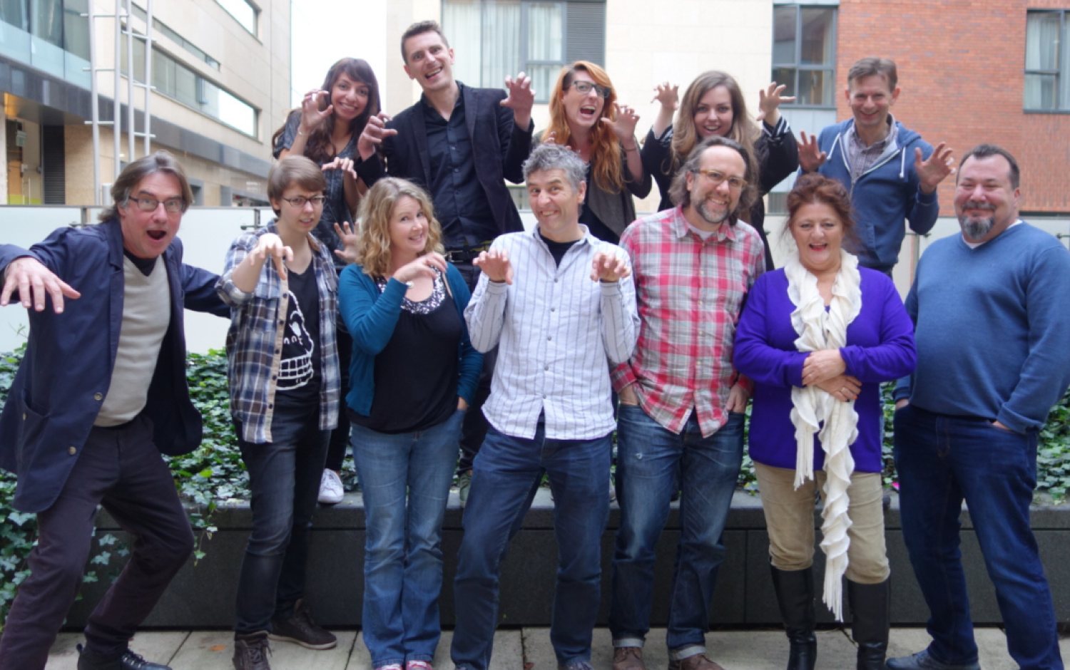 Group posing outdoors making playful claw gestures in front of a building.