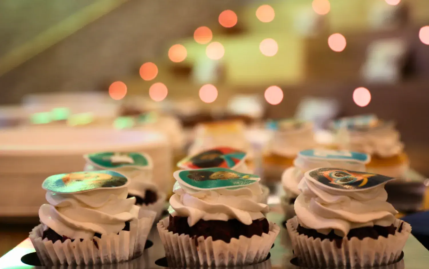 Close-up of cupcakes topped with edible images of animated characters and logos.