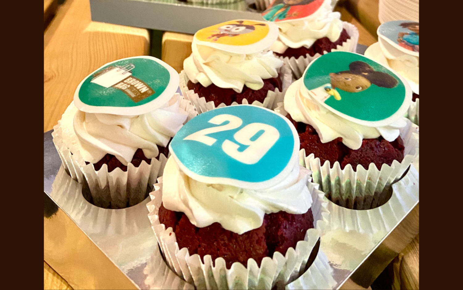 Cupcakes with white frosting and edible toppers featuring animated characters and the number 29.