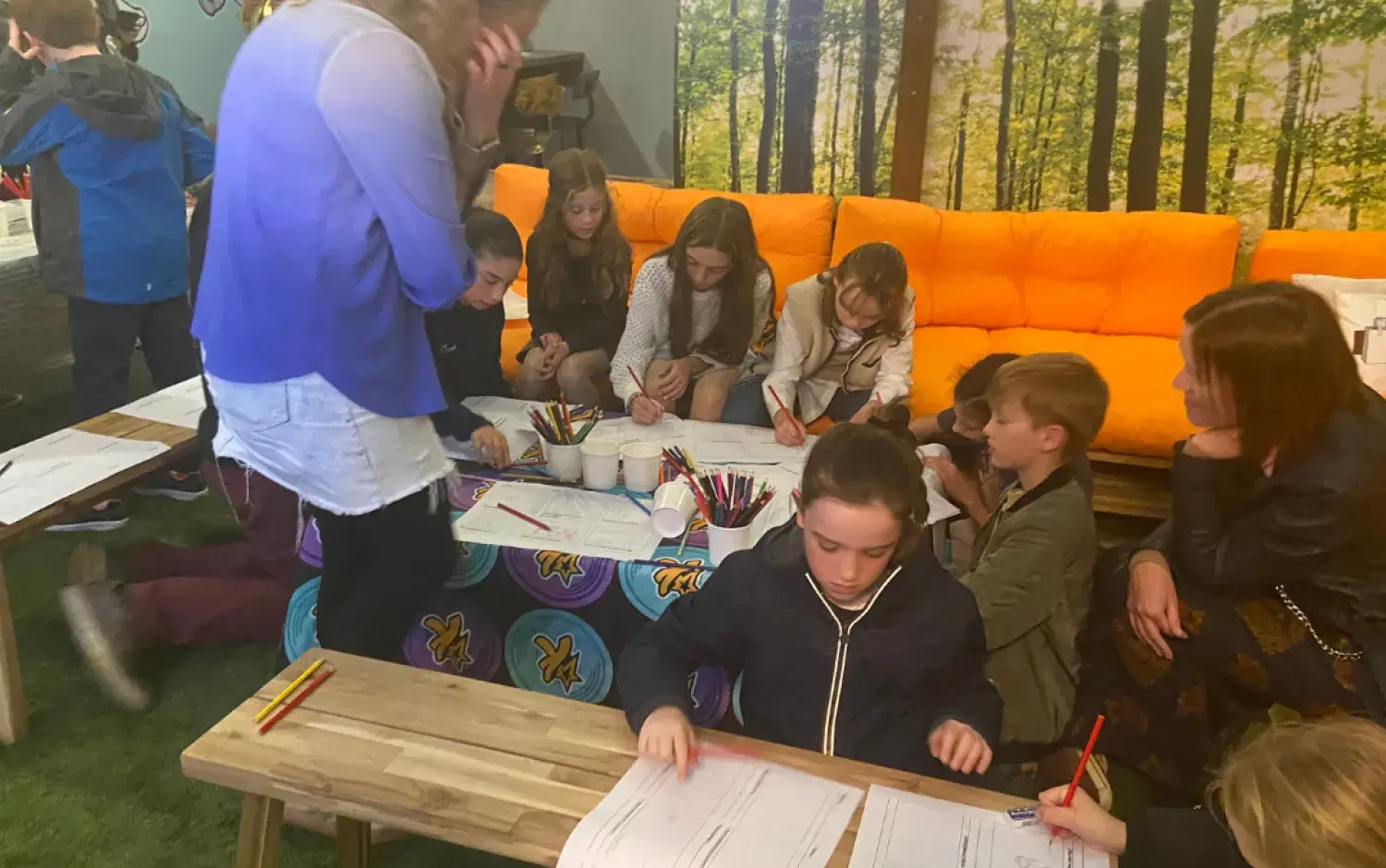 Children seated around a table drawing and coloring during an indoor activity session.