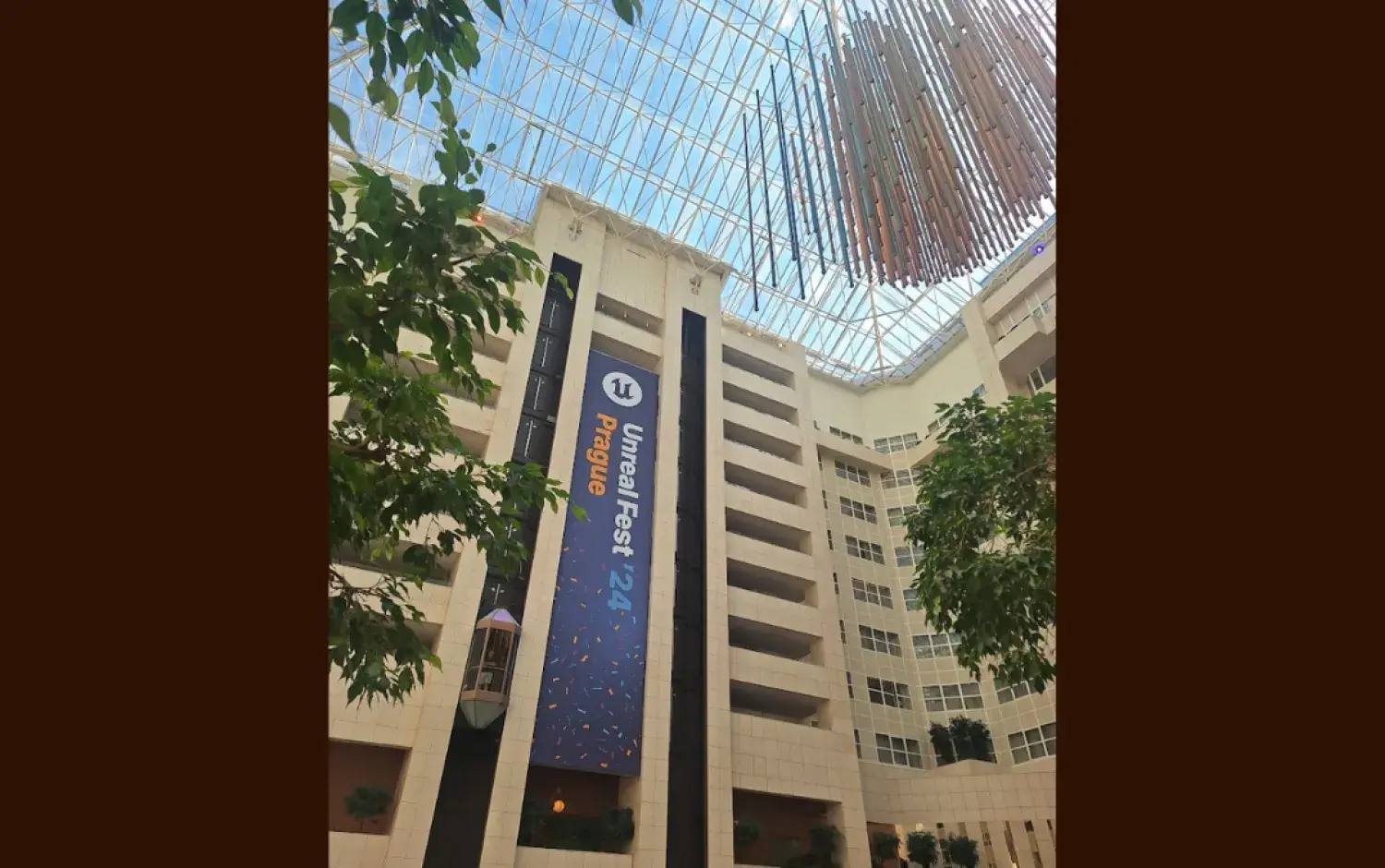 Tall indoor atrium with a large vertical banner reading “Unreal Fest Prague ’24” hanging from the upper floors.