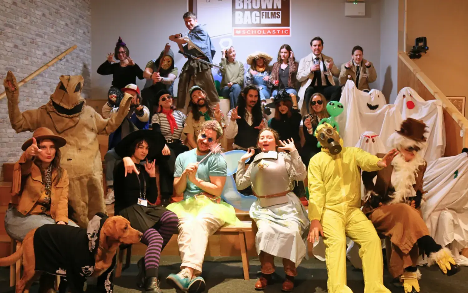 Large group dressed in creative costumes posing on tiered seating for a themed event at Brown Bag Films.