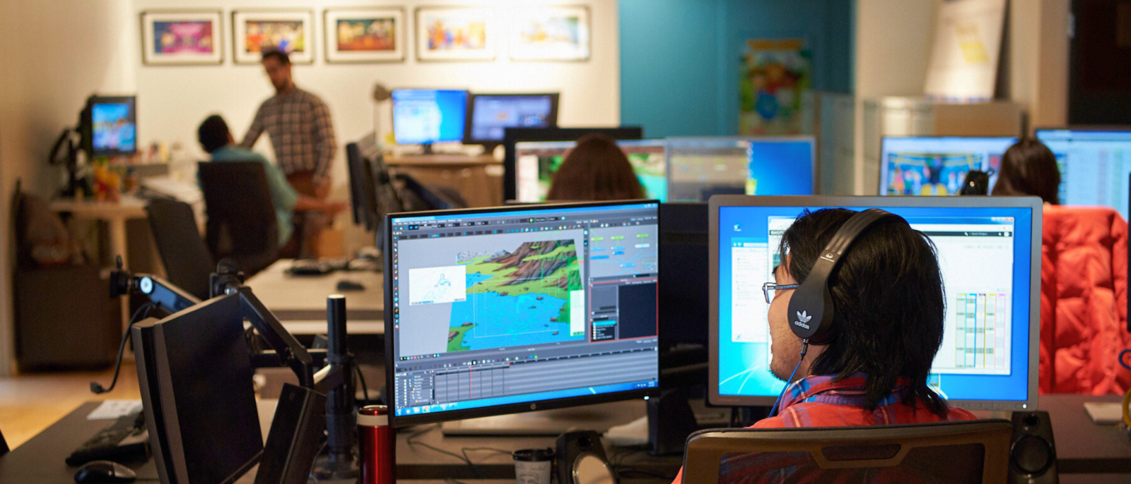 Two people collaborating at a desk, one using a digital tablet and the other looking at the computer screen.