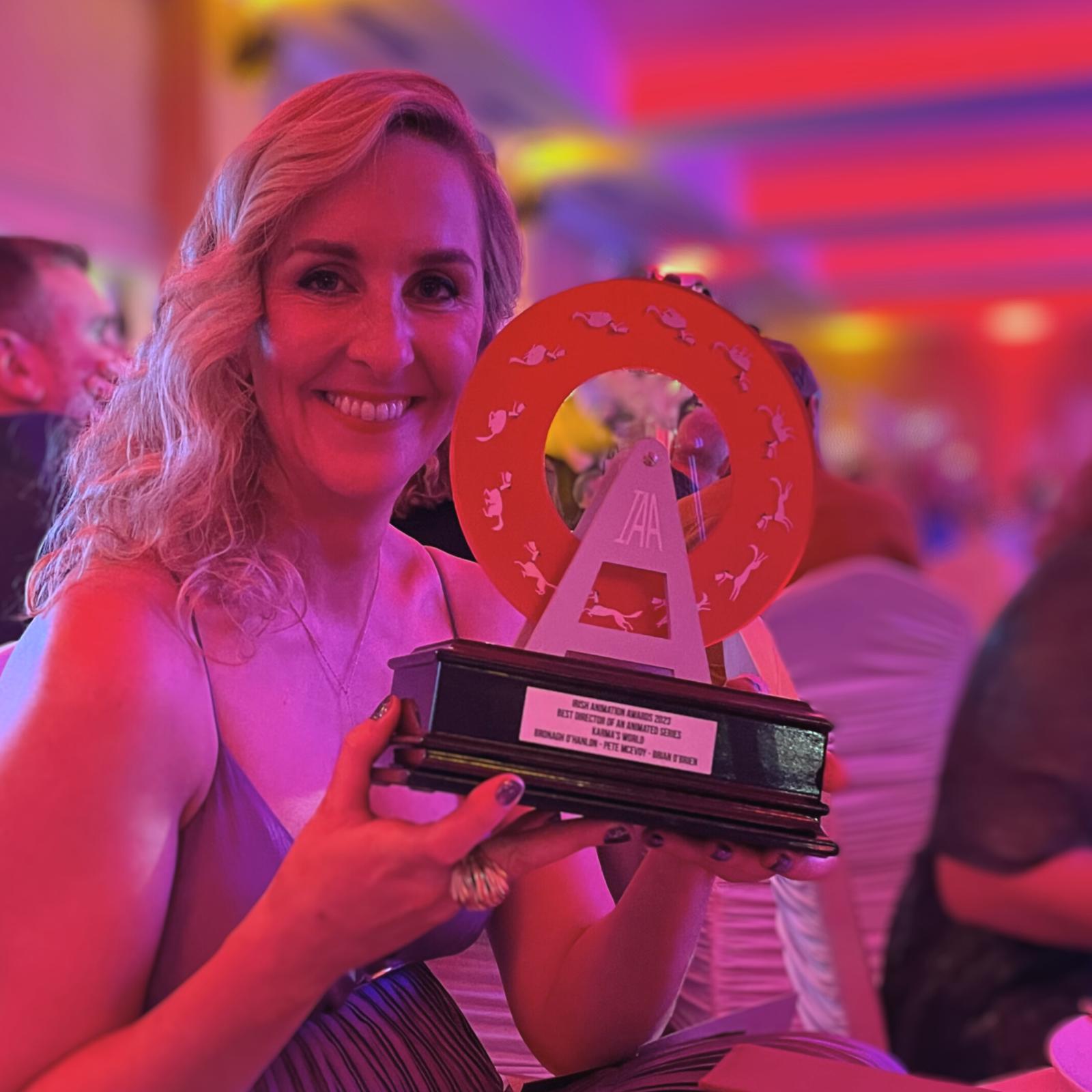 Person holding Irish Animation Award trophy with red circular design and engraved plaque.