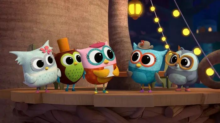 Five owlets standing together under string lights.